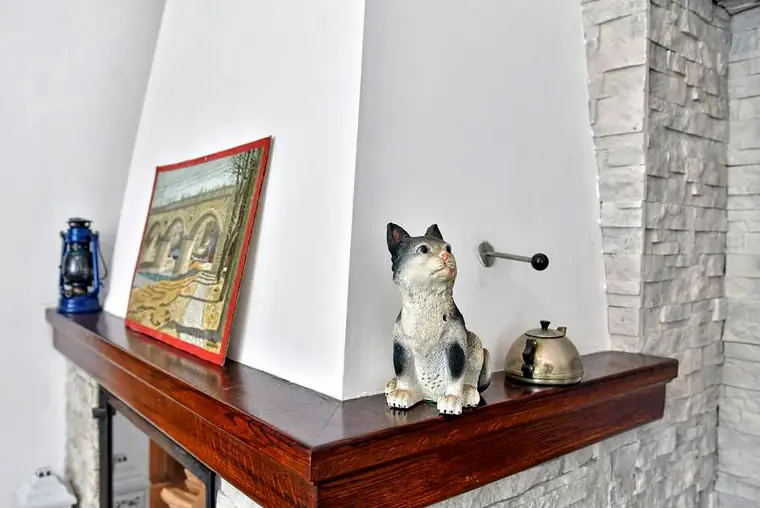 Lampa naftowa, obraz i porcelanowa figurka kota na kominku