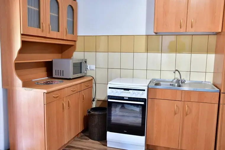 Kuchnia z drewnianymi frontami, kuchenką i zlewozmywakiem